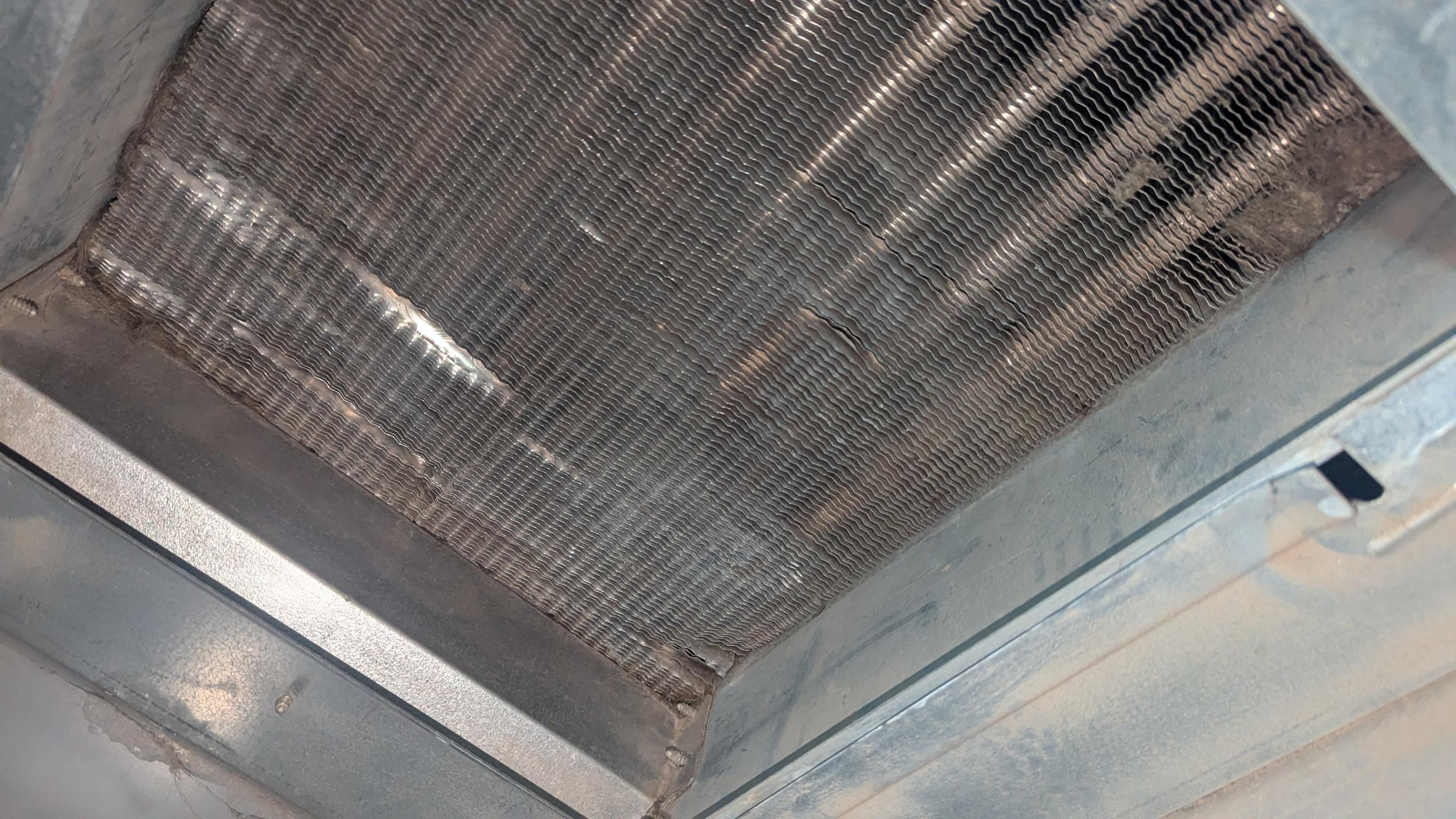 A technician inspecting a dusty furnace heat exchanger