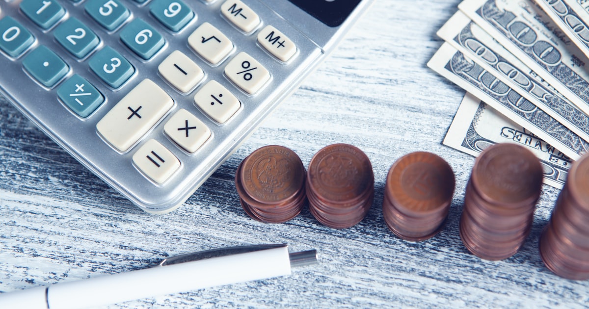 a calculator, pen, and money on a table