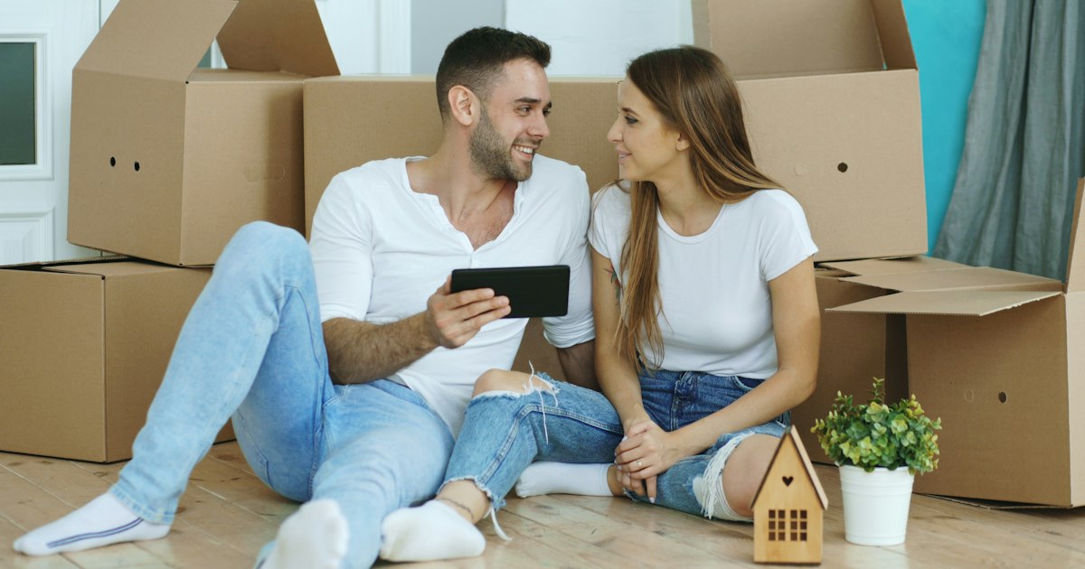 Couple looking at phone surrounded by moving boxes