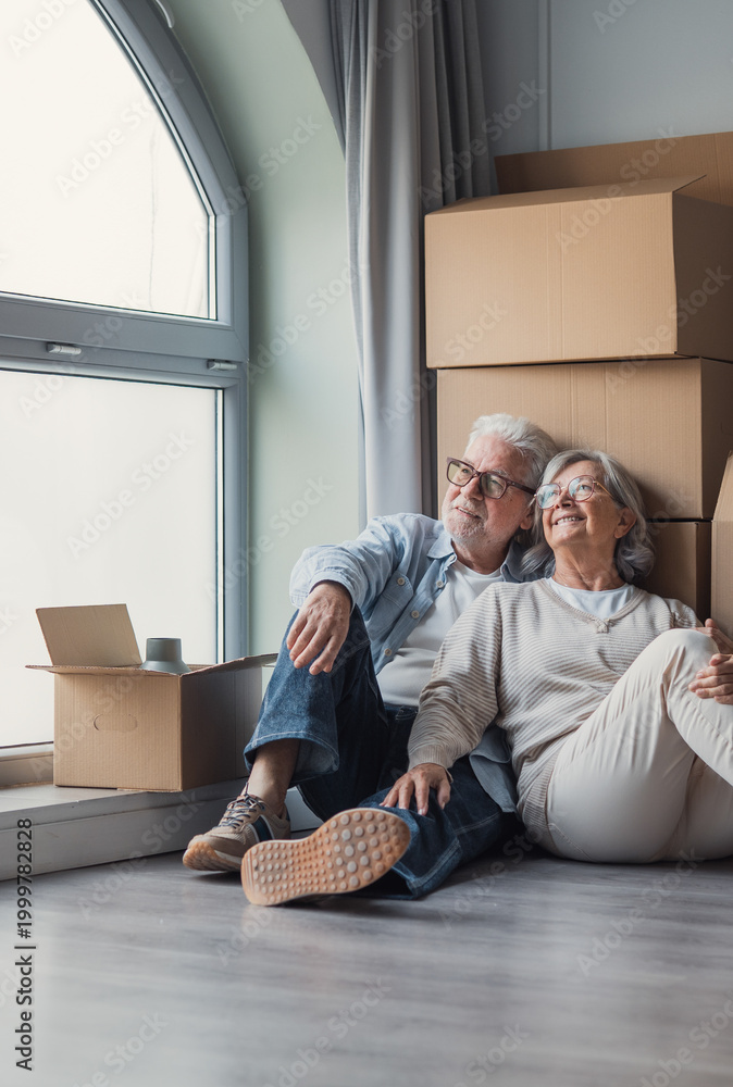 Senior couple carrying moving boxes into their new home
