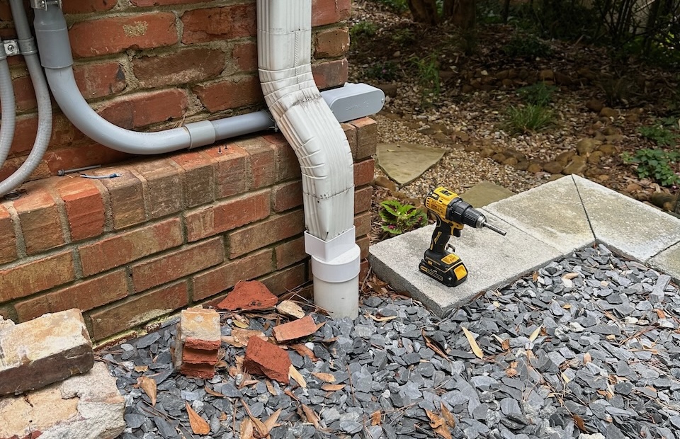 A gutter downspout draining rainwater away from a house foundation