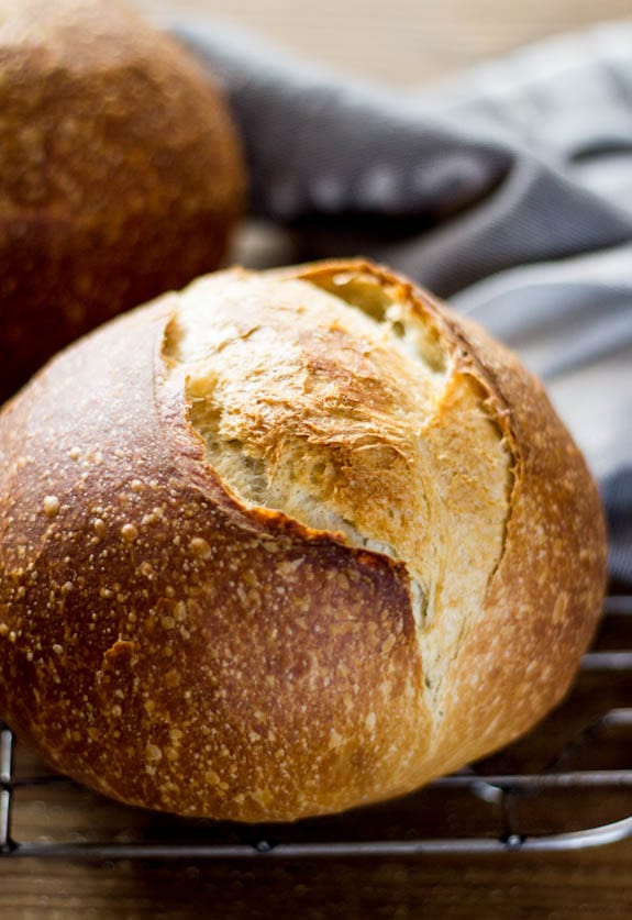 Golden, freshly scored sourdough bread on a floured surface