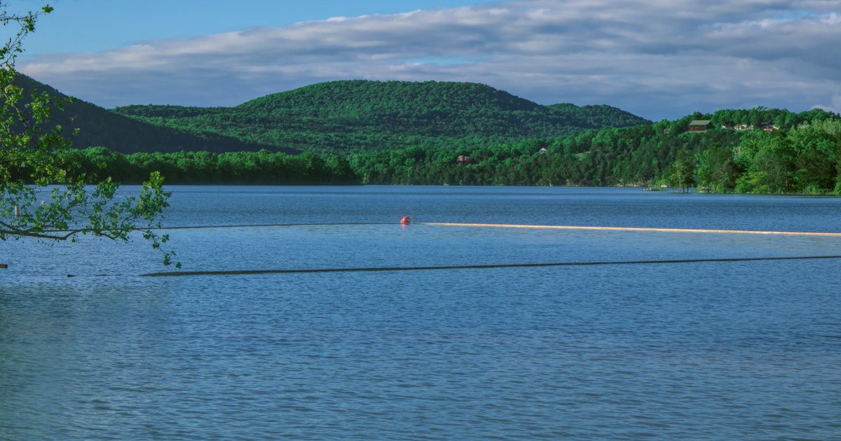 person in red shirt and black pants standing on white sand near body of water during