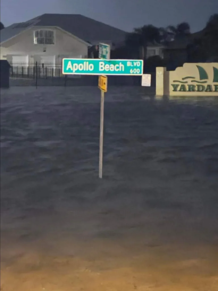 Apollo Beach Blvd street sign standing in hurricane storm surge flood water at dusk, Apollo Beach, FL