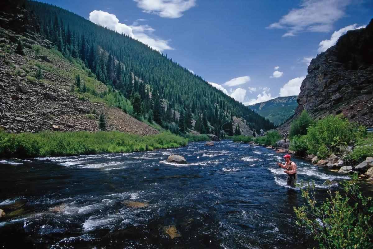 A fly fisherman casts into a scenic Colorado Gold Medal river during the sunset rise.
