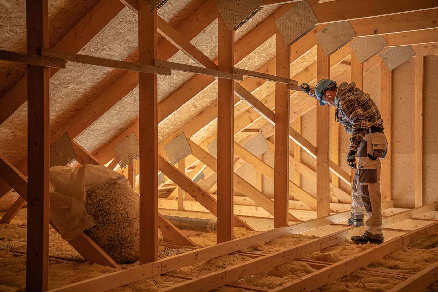 Home inspector checking attic insulation and roof structure