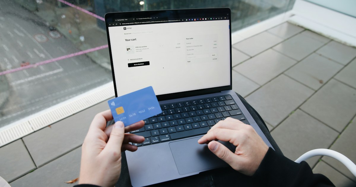 A person sitting in a chair with a laptop and a credit card